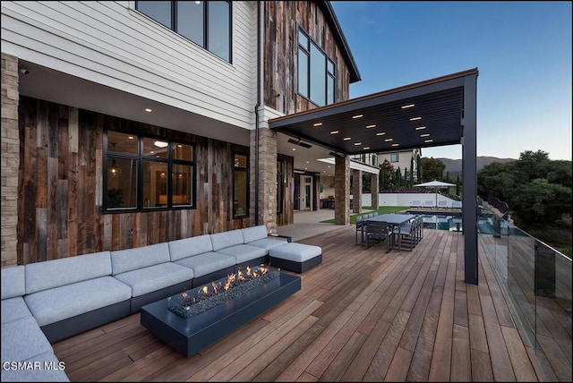 wooden deck featuring an outdoor living space with a fire pit