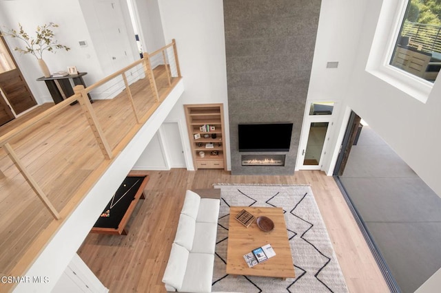 living room featuring a large fireplace, light wood-type flooring, and a high ceiling