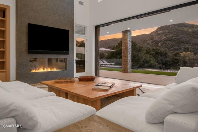 living room featuring a large fireplace, built in shelves, light hardwood / wood-style flooring, and plenty of natural light