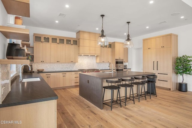 kitchen with pendant lighting, light brown cabinets, sink, light wood-type flooring, and stainless steel appliances