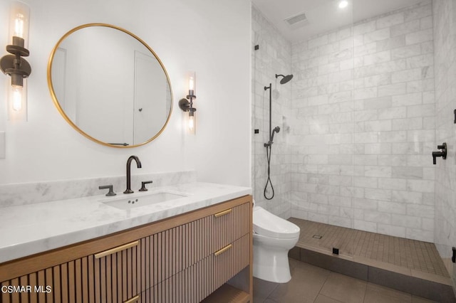 bathroom with a tile shower, tile patterned flooring, vanity, and toilet