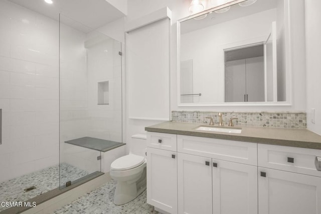 bathroom featuring tasteful backsplash, tile patterned flooring, toilet, a shower with door, and vanity