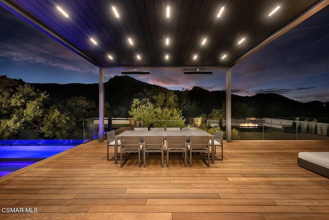 deck at dusk with a mountain view and a pool