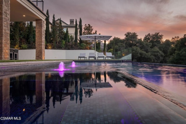 pool at dusk with a patio area