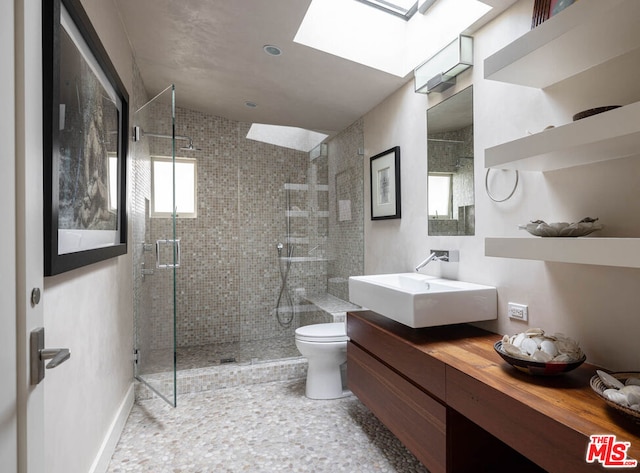 bathroom with toilet, an enclosed shower, vaulted ceiling with skylight, and vanity