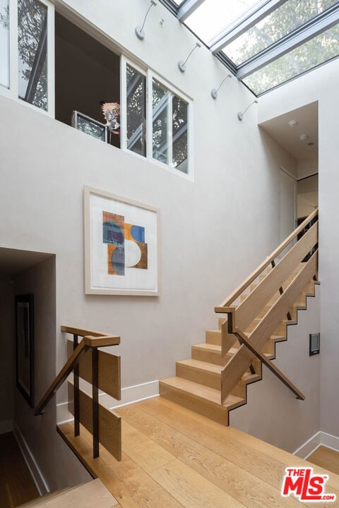 stairs featuring hardwood / wood-style floors and a skylight