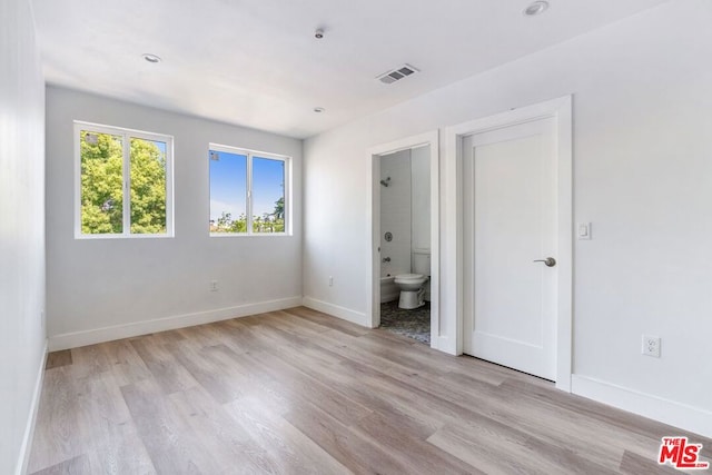 unfurnished bedroom with light hardwood / wood-style flooring and ensuite bathroom