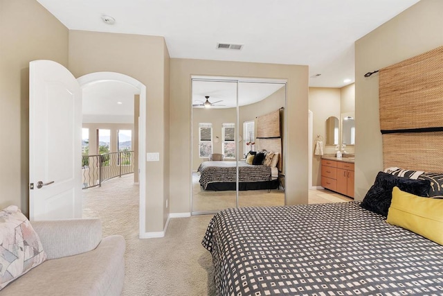 bedroom with a closet, connected bathroom, and light colored carpet