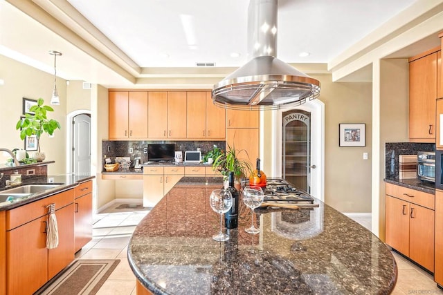 kitchen featuring a large island, decorative backsplash, light tile patterned floors, island range hood, and sink