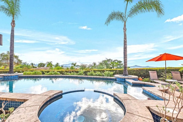 view of swimming pool with an in ground hot tub and a mountain view