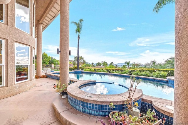 view of swimming pool featuring an in ground hot tub and a patio