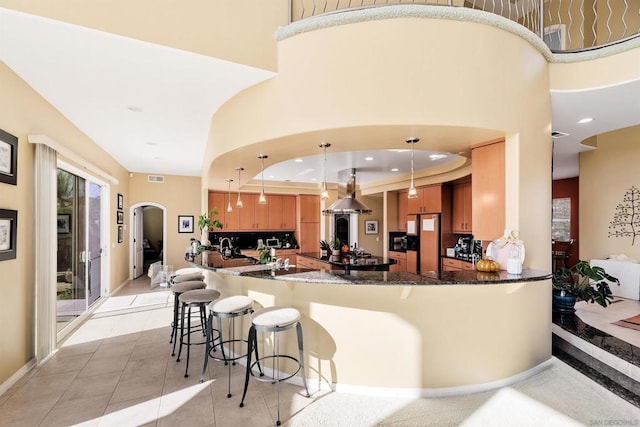 kitchen featuring kitchen peninsula, island exhaust hood, light tile patterned floors, dark stone counters, and pendant lighting