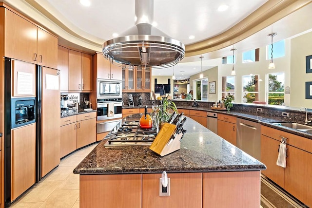 kitchen featuring island exhaust hood, appliances with stainless steel finishes, decorative light fixtures, and dark stone counters