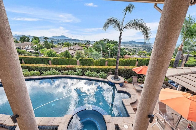 view of pool with an in ground hot tub, a mountain view, and a patio area