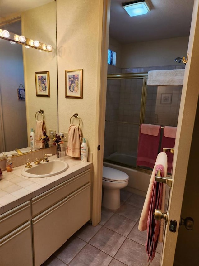 full bathroom with tile patterned flooring, vanity, toilet, and bath / shower combo with glass door