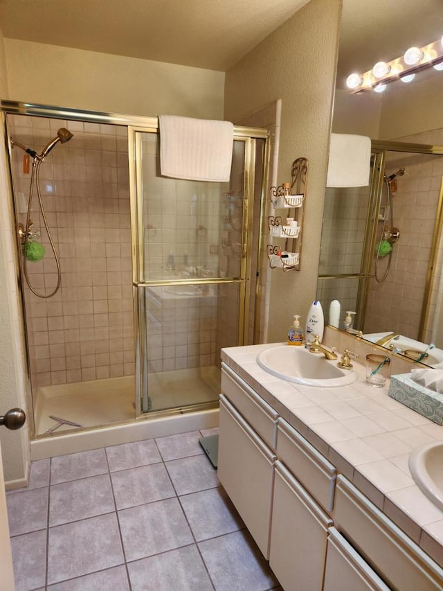 bathroom with walk in shower, vanity, and tile patterned floors