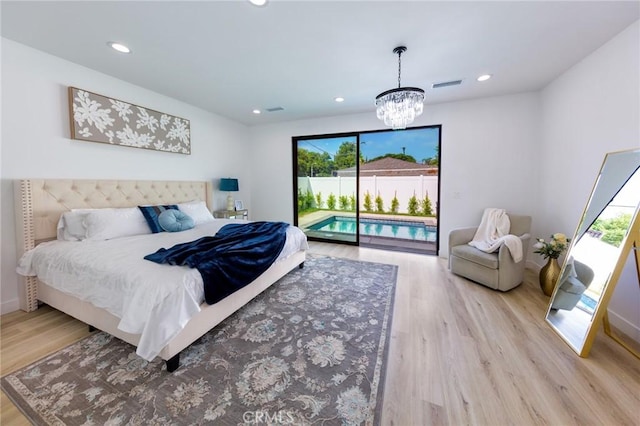 bedroom featuring access to outside, an inviting chandelier, multiple windows, and light hardwood / wood-style floors