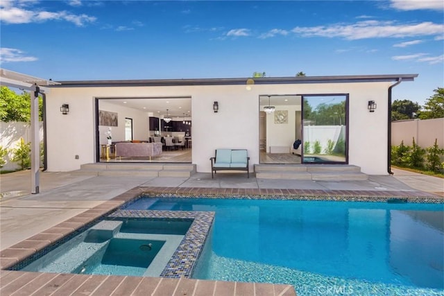 rear view of property with a patio and a pool with hot tub