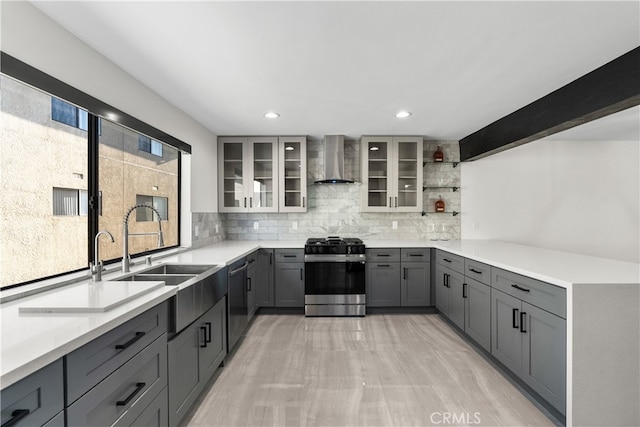 kitchen with wall chimney range hood, a healthy amount of sunlight, stainless steel appliances, and gray cabinets