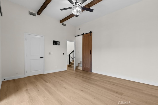 unfurnished bedroom with light wood-type flooring, a barn door, ceiling fan, beamed ceiling, and high vaulted ceiling