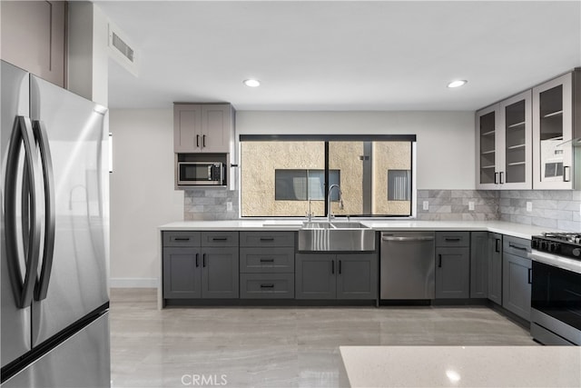 kitchen with appliances with stainless steel finishes, sink, decorative backsplash, and gray cabinets