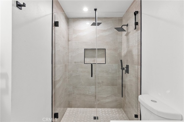 bathroom with a shower with shower door and toilet