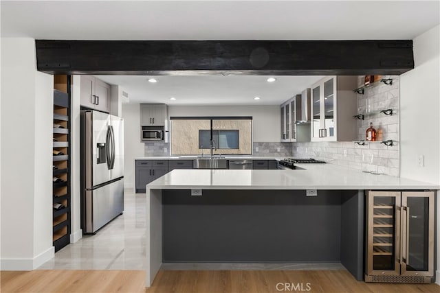 kitchen featuring wine cooler, kitchen peninsula, gray cabinetry, and stainless steel appliances