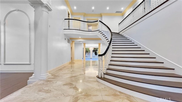 staircase featuring ornate columns and a high ceiling