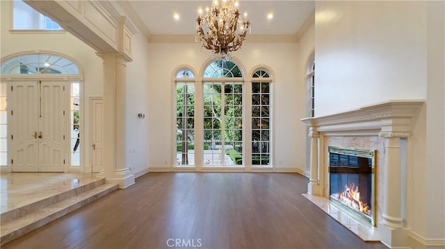 entrance foyer with dark hardwood / wood-style floors, a high end fireplace, a towering ceiling, and a notable chandelier