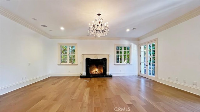 unfurnished living room featuring plenty of natural light, crown molding, a fireplace, and hardwood / wood-style floors