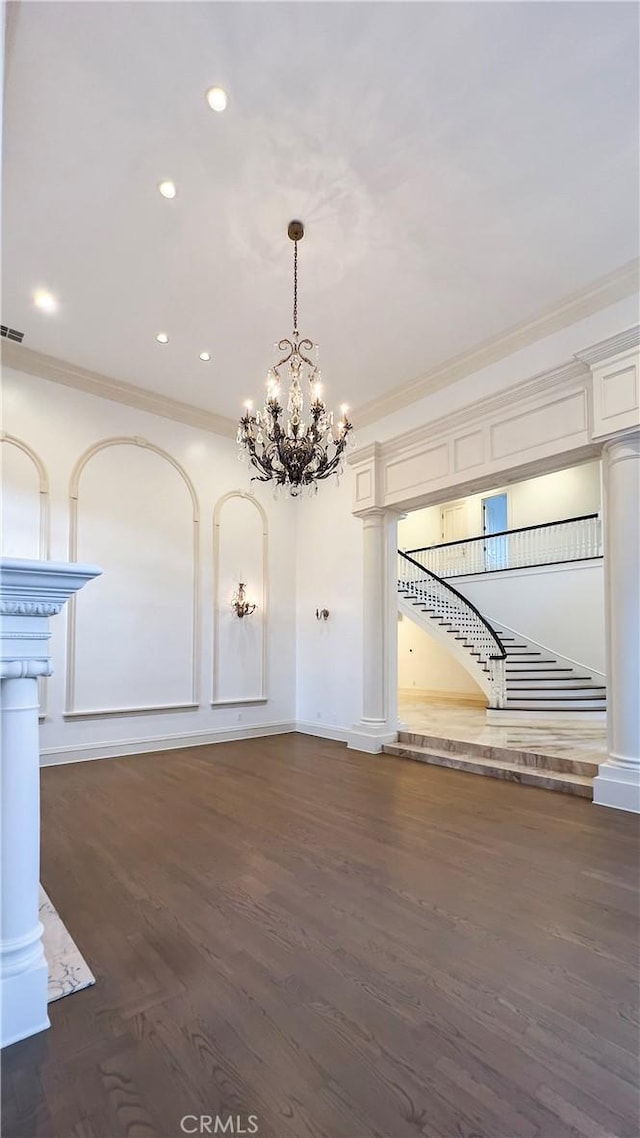 unfurnished dining area featuring dark hardwood / wood-style flooring, crown molding, and a chandelier