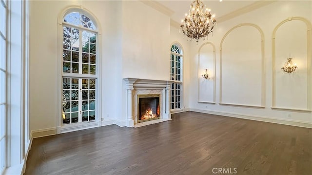 unfurnished living room with dark wood-type flooring, a chandelier, a fireplace, and a towering ceiling