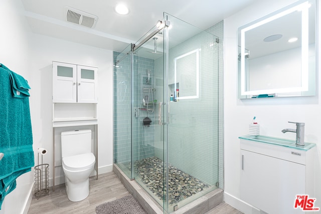 bathroom with sink, wood-type flooring, toilet, and a shower with door