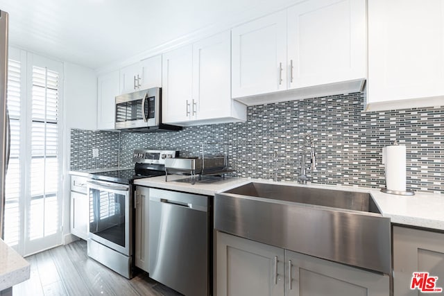 kitchen with appliances with stainless steel finishes, white cabinets, tasteful backsplash, and light stone countertops