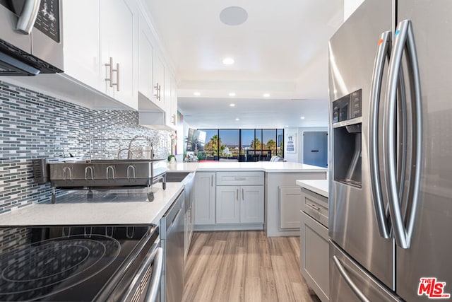 kitchen featuring gray cabinets, kitchen peninsula, decorative backsplash, light hardwood / wood-style flooring, and stainless steel appliances