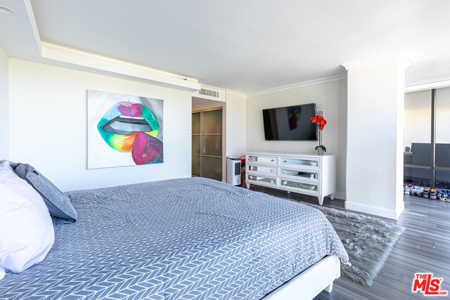 bedroom featuring ornamental molding, a wall of windows, and hardwood / wood-style flooring