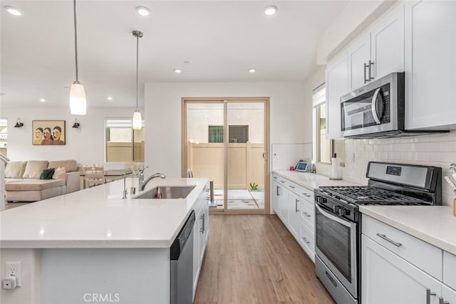 kitchen featuring an island with sink, white cabinetry, sink, and stainless steel appliances