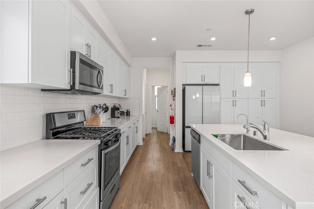 kitchen featuring white cabinets, appliances with stainless steel finishes, hanging light fixtures, and sink