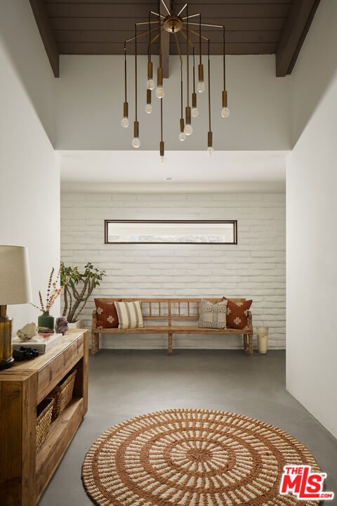 interior space featuring beam ceiling, concrete floors, wooden ceiling, and brick wall