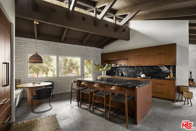 kitchen featuring a center island, lofted ceiling with beams, brick wall, decorative light fixtures, and a breakfast bar area