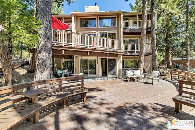 back of property featuring a balcony and a deck