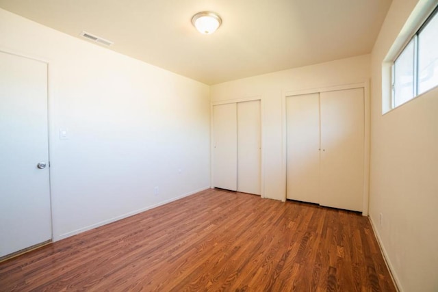 unfurnished bedroom featuring two closets and dark hardwood / wood-style floors