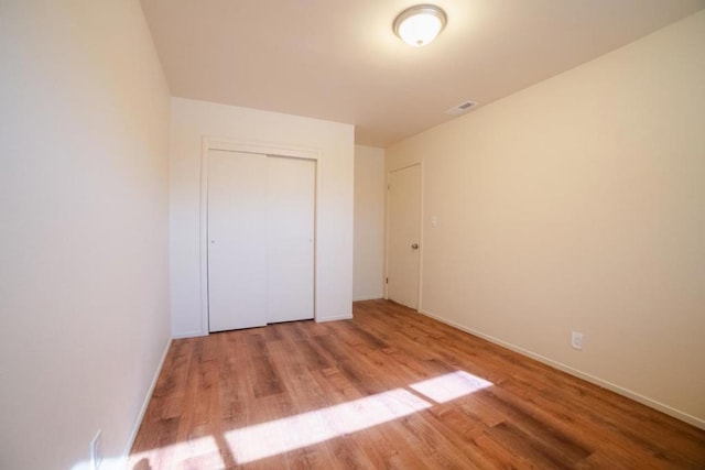 unfurnished bedroom featuring light hardwood / wood-style flooring and a closet