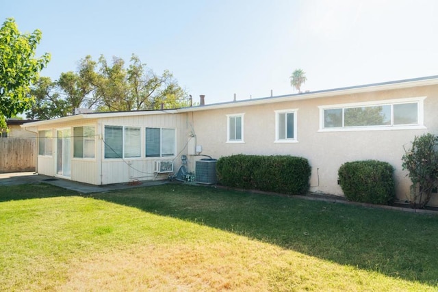 back of house with cooling unit and a lawn