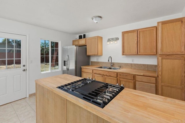 kitchen featuring gas stovetop, stainless steel fridge, sink, and a healthy amount of sunlight