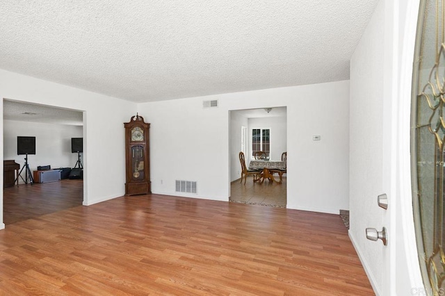 spare room with a textured ceiling and light hardwood / wood-style floors