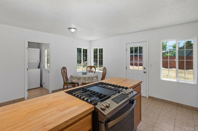 kitchen with light tile patterned floors, high end stove, and stacked washer and dryer