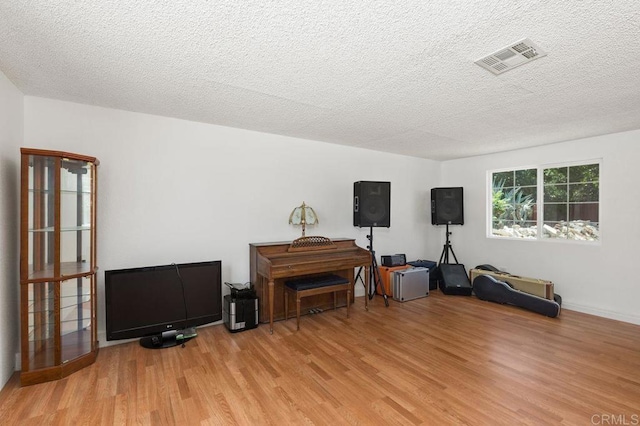 miscellaneous room featuring a textured ceiling and light hardwood / wood-style flooring