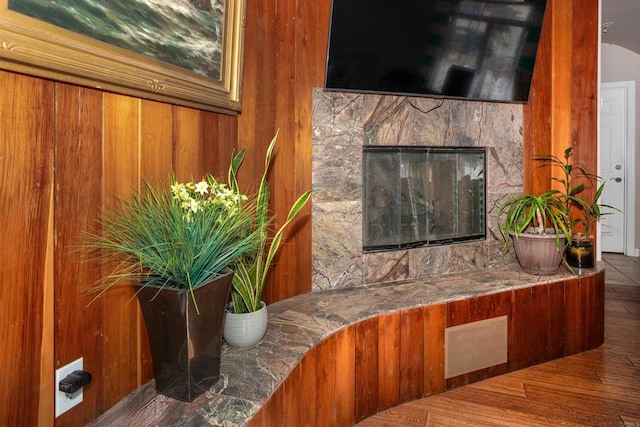 room details featuring wooden walls, a fireplace, and hardwood / wood-style floors