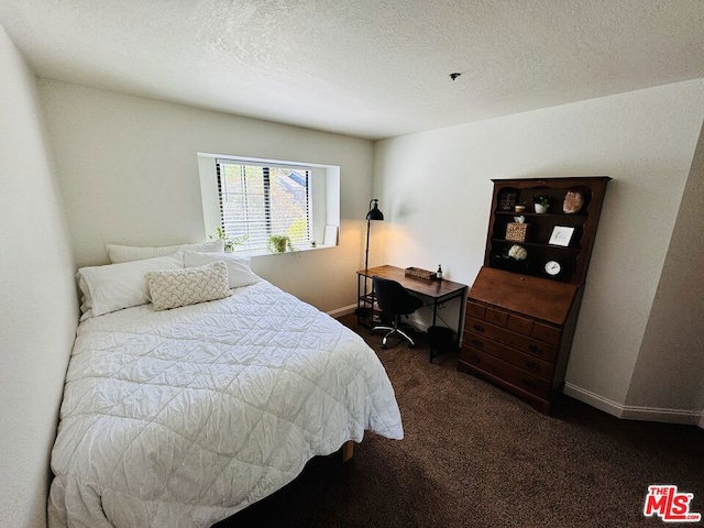 bedroom with a textured ceiling and dark carpet